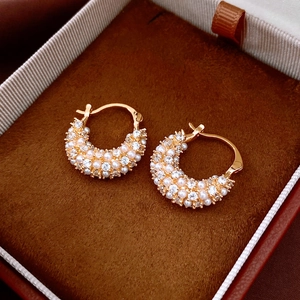Close-up of 18k gold plated pearl earrings with crystals in a brown velvet jewelry box