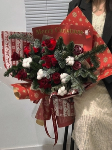 Christmas bouquet detail featuring red roses and pines wrapped in snowflake foil paper