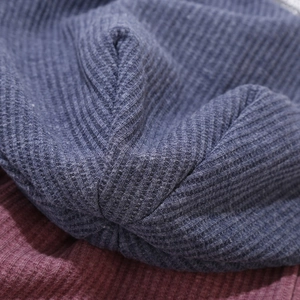 Vue macro du tricot gaufré bleu marine et bordeaux montrant la texture douce du bonnet tricoté