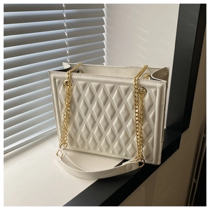 Detailed macro view of white quilted faux leather texture and gold chain on tote bag