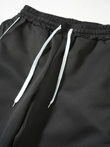 Detail of black tactical pants with elastic waistband and white adjustable drawstring