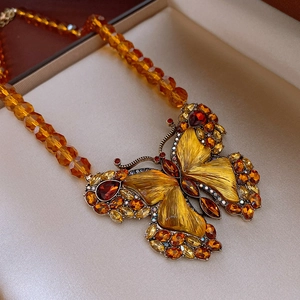 Macro detail of amber butterfly pendant with inlaid crystals and beaded chain