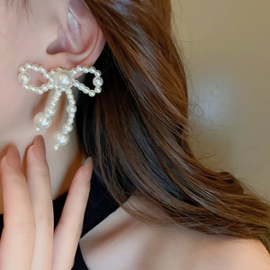 Elegant bow-knot pearl tassel stud earrings on female model with graceful style