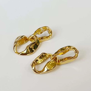 Minimalist gold chain earrings with irregular lava texture finish on a clean white background