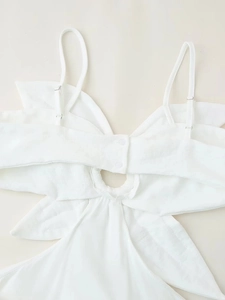 Détail de robe blanche avec fines bretelles réglables et bouton de fermeture au dos