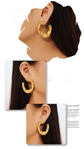 Detail of oversized U-shaped chunky gold hoop earrings worn by a model