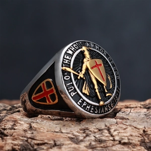 Macro shot of silver and gold shield ring with biblical cross engraving on wood