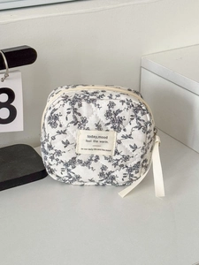 Macro detail of quilted cotton pouch featuring black floral pattern and ribbon zipper