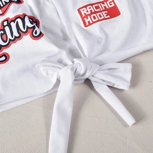 Dettaglio del crop top bianco Racing Mode con grafica frontale e orlo con nodo