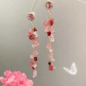 Detail of long tassel earrings with pink crystals, rhinestones and golden chains