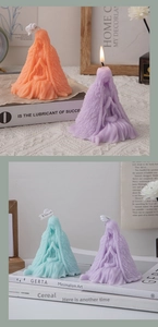 Three sculpted robe candles in orange, purple and cyan on aesthetic background