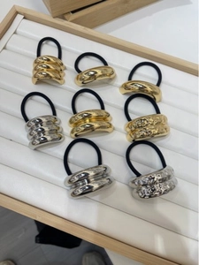 Close-up of minimalist gold and silver metal hair ties with various textured finishes