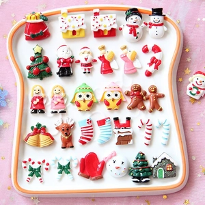 Flat lay of 25 miniature Christmas resin charms including Santa and snowman on a white tray