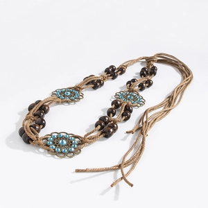 Detail of bohemian waist rope with wooden beads and bronze flowers with blue rhinestones