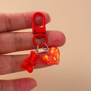 Cute red resin bear and heart keychain charm with matching red metal clasp on hand