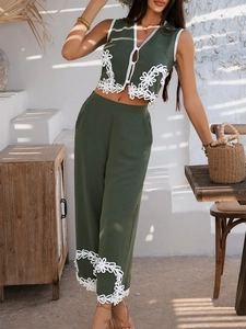 Détail de la broderie florale blanche sur le haut sans manches et le pantalon vert foncé