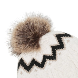 Detailansicht der Strickmütze mit weißen Zickzack-Mustern und flauschigem Kunstfell-Pompon