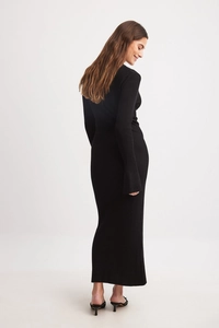 Detail view of black ribbed knit long sleeve maxi dress showing texture and slim fit