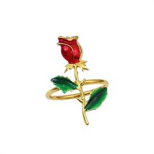 Detailed view of a gold rose napkin ring featuring red enamel petals and green leaves