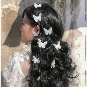 Detail of white butterfly embroidery hair clips worn on long wavy hair in sunlight