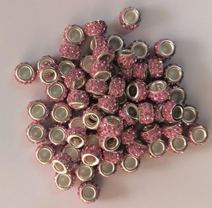 Close-up of pink rhinestone clay beads with metal grommets for DIY jewelry making