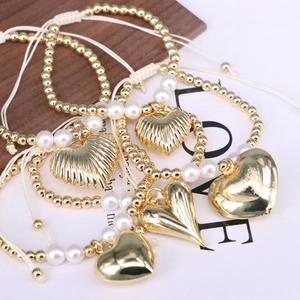 Handmade gold beaded bracelets with pearls and heart pendants on braided cord
