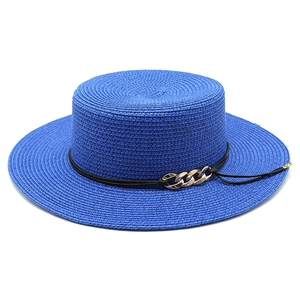 Détail d'un chapeau de paille bleu avec ruban noir et boucle en chaîne dorée chic