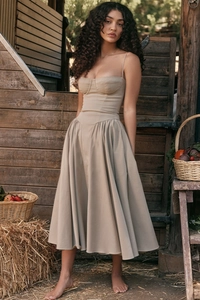 Detail of khaki corset-style midi dress with slim straps in a rustic farm setting