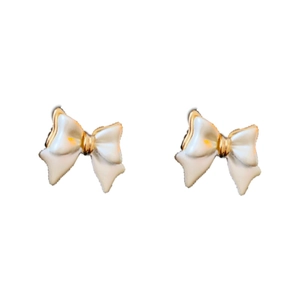 Boucles d'oreilles nœuds plaquées or 14 carats avec émail blanc sur fond blanc épuré