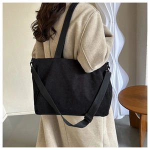 Detailed view of black corduroy tote bag showing textured fabric and wide shoulder strap