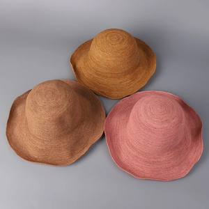 Detail of three colorful hand-woven raffia sun hats in tan, yellow, and dusty pink