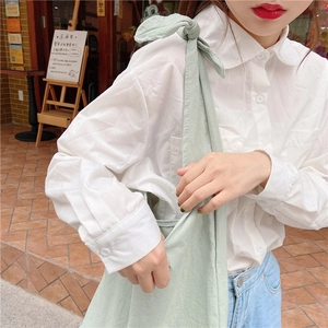 Detail of light green canvas tote bag featuring a decorative large bow shoulder strap