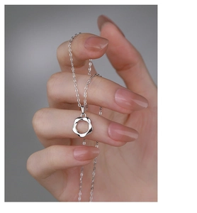 Close-up of S925 sterling silver Mobius loop pendant held by hand on a delicate chain