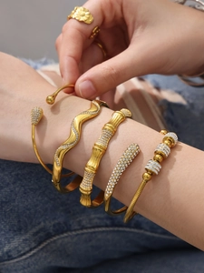 Vue détaillée de bracelets dorés empilés avec des lignes ondulées et un décor de zircons brillants
