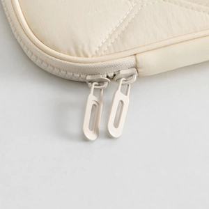 Detail view of beige quilted tablet sleeve with dual zippers and textured fabric