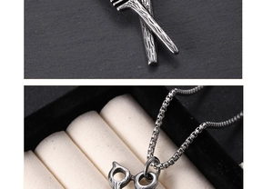 Detailed view of silver scissor and comb pendant on a black velvet necklace stand