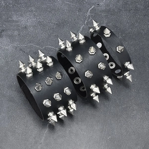Detailed view of black punk PU leather bracelets with silver metal spikes on a stone surface