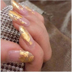 Detailed view of irregular gold foil flakes on oval nails for creative DIY nail art designs