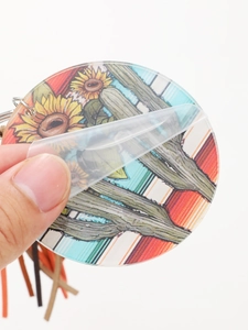 Close-up of western acrylic charm with sunflower and cactus print removing protective film