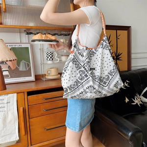 Detailed shoulder strap view of a black paisley tote bag with orange checkered handle