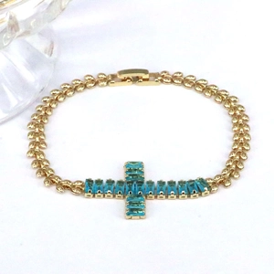 Gold leaf chain bracelet featuring a micro-pave zircon cross with blue stones
