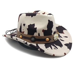 Detail of cow print cowboy hat with leather band, gold beads and eagle badge