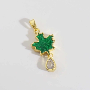 Détail macro du pendentif feuille d'érable plaqué or avec émail vert et zircon goutte