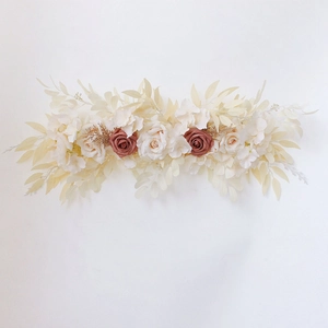 Detail of cream and dusty rose artificial flower row with faux foliage on white background
