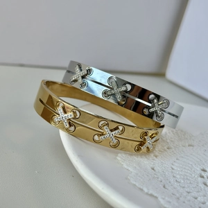 Detail of gold and silver crisscross bracelets with rhinestone inlay on a white porcelain dish