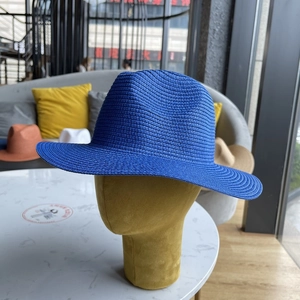Detailed close-up of a dark blue woven straw fedora hat with a classic dented crown