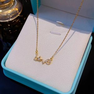 Goldene Halskette mit Love-Anhänger und Krone in einer hellblauen Schmuckschatulle