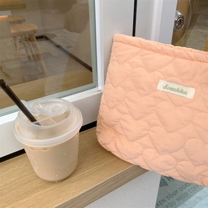 Quilted heart peach pouch with Sozakka label on a wooden window sill at a cafe