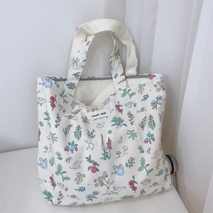 Detail of cream canvas handbag featuring colorful garden illustrations and top zipper