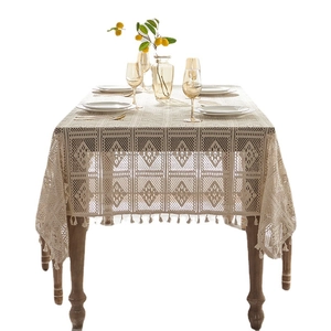 Elegant beige lace tablecloth with geometric patterns and tassel edges on wooden table